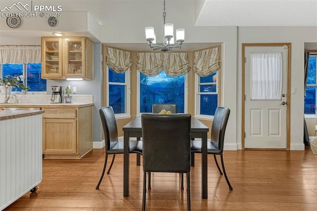 dining room with baseboards, a notable chandelier, and light wood-style flooring