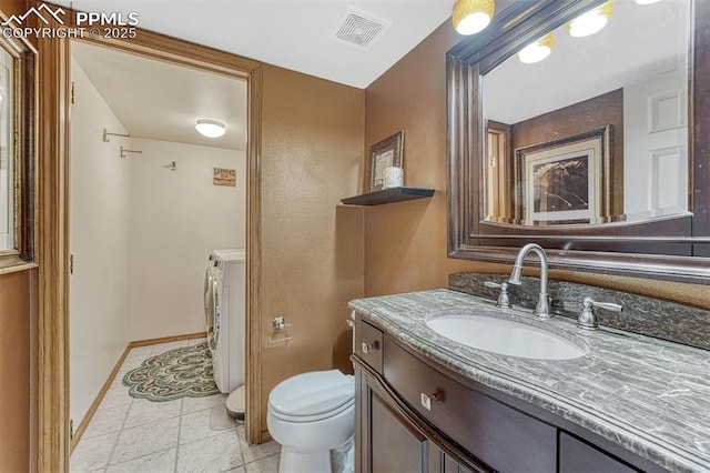 bathroom featuring visible vents, vanity, washing machine and dryer, toilet, and baseboards