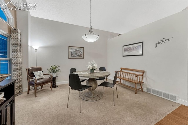 dining room with baseboards, vaulted ceiling, wood finished floors, and visible vents