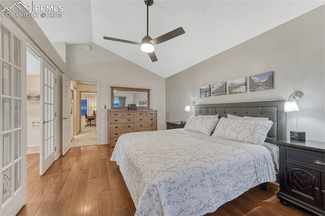 bedroom featuring lofted ceiling, wood finished floors, ceiling fan, a textured ceiling, and french doors