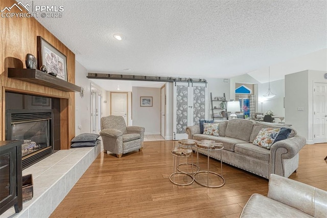 living area with a textured ceiling, wood finished floors, and a fireplace