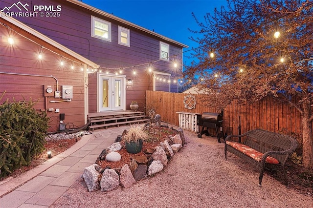 back of house at night featuring fence