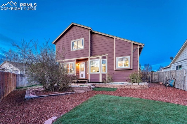 rear view of house featuring a lawn and a fenced backyard