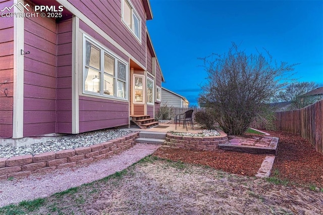 view of side of property featuring a patio, a fenced backyard, and entry steps
