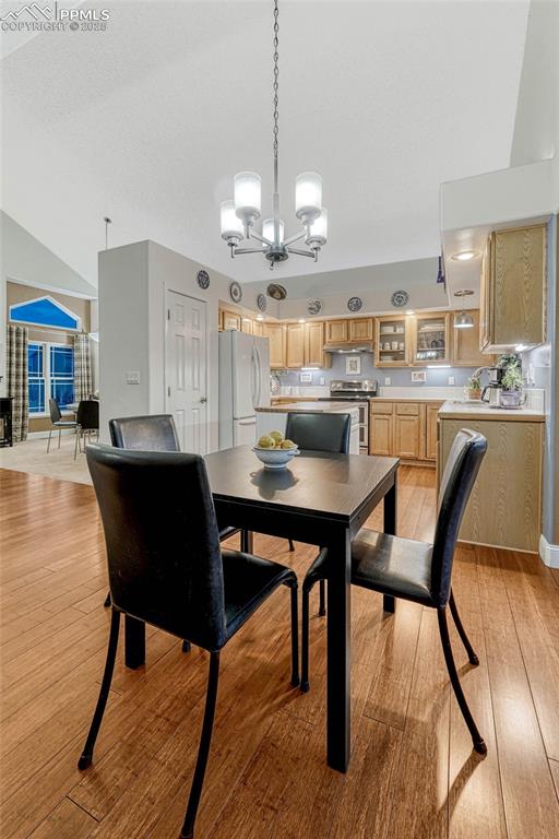dining room featuring vaulted ceiling, light wood finished floors, and a chandelier