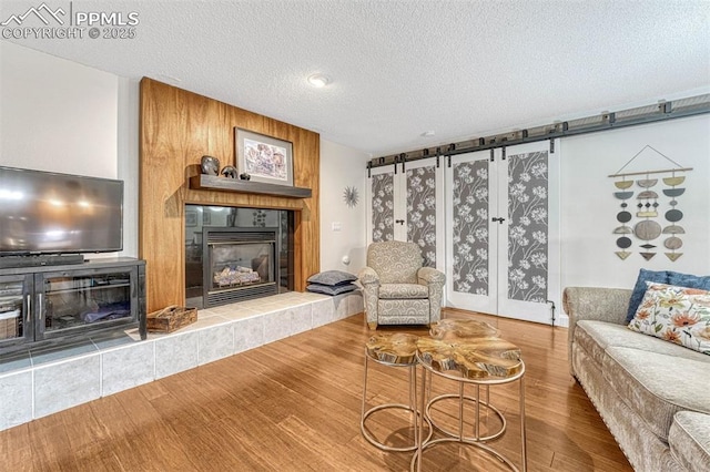 living area with a textured ceiling, wood finished floors, and a fireplace