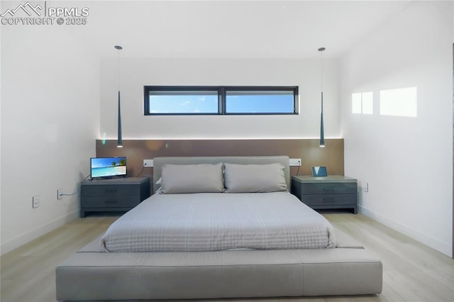 bedroom featuring light wood finished floors, baseboards, and multiple windows