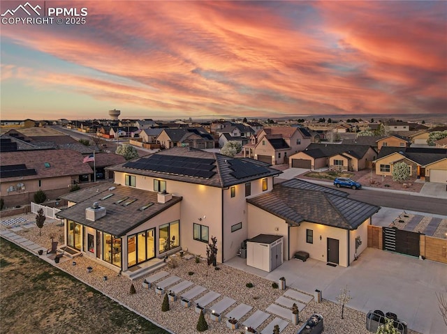 rear view of property with a residential view, a fenced backyard, a gate, solar panels, and driveway
