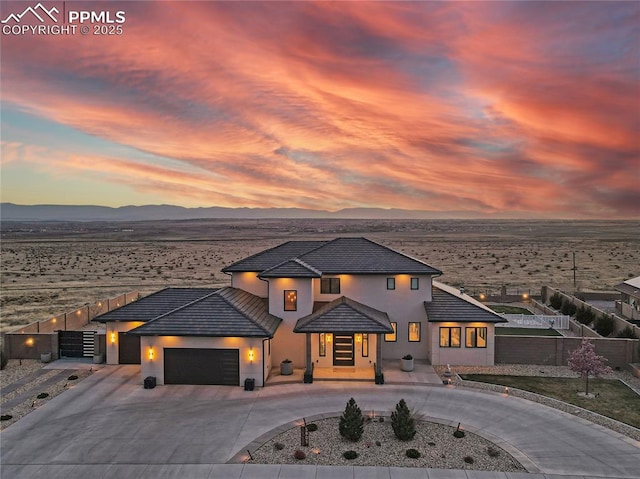 view of front facade with a tiled roof, a mountain view, fence, a garage, and curved driveway