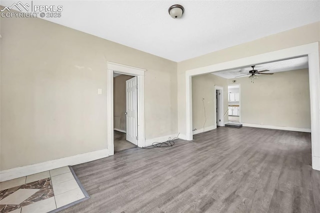 unfurnished room with wood finished floors, ceiling fan, and baseboards