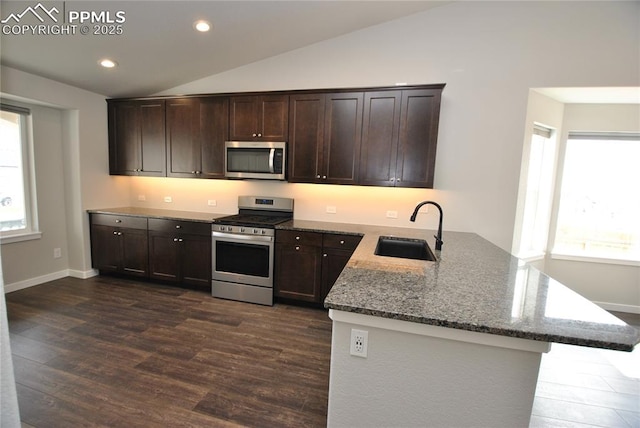 kitchen featuring stone countertops, dark wood-style flooring, vaulted ceiling, stainless steel appliances, and a sink