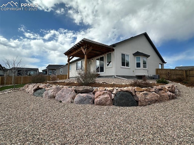 rear view of property with fence and stucco siding
