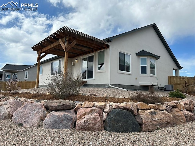 rear view of property with central AC unit, a pergola, stucco siding, and fence