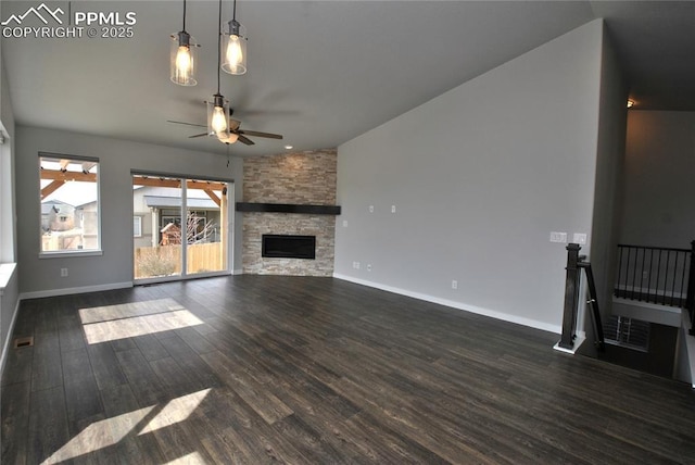 unfurnished living room featuring dark wood-style flooring, baseboards, a ceiling fan, and a stone fireplace