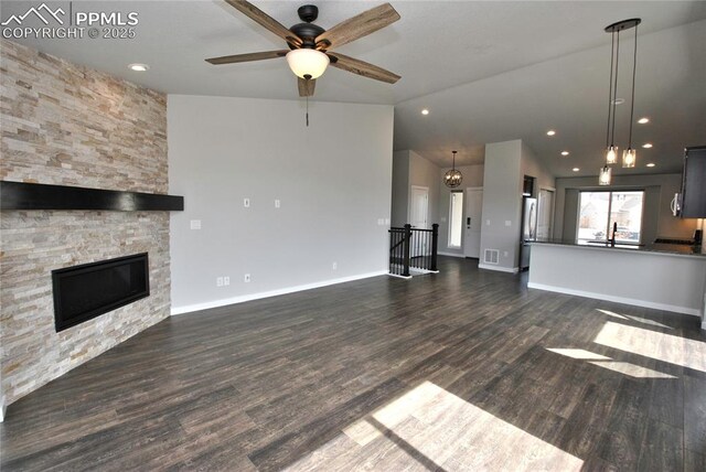 unfurnished living room with dark wood-style flooring, visible vents, a stone fireplace, and a ceiling fan