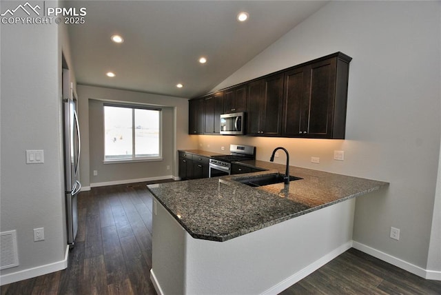 kitchen with dark stone countertops, dark wood-style floors, a sink, and appliances with stainless steel finishes