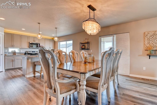 dining area with recessed lighting, light wood finished floors, a notable chandelier, and baseboards