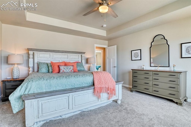 carpeted bedroom featuring a tray ceiling, baseboards, and a ceiling fan