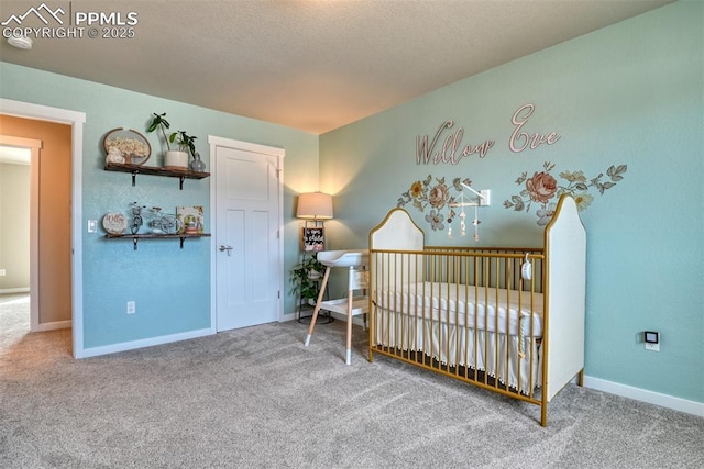 carpeted bedroom with baseboards, a crib, and a textured ceiling