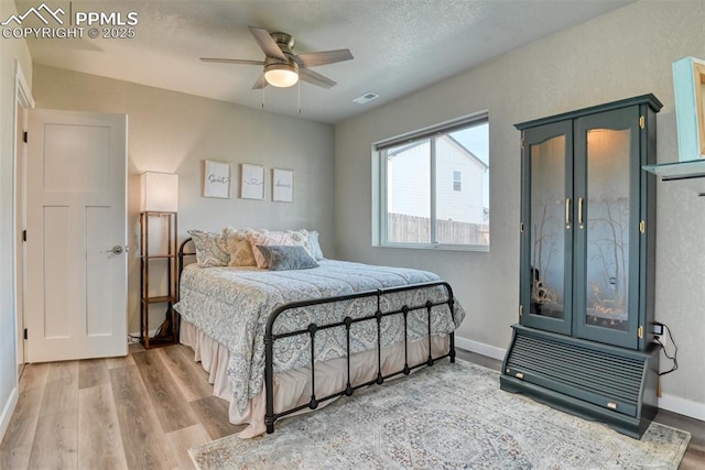 bedroom with visible vents, baseboards, wood finished floors, and a textured ceiling