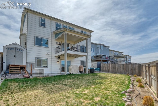 back of house with a yard, a fenced backyard, a storage shed, and an outbuilding