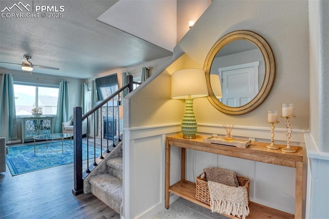 stairs with ceiling fan, wood finished floors, and a textured ceiling