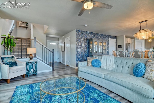 living area with stairway, an accent wall, wallpapered walls, and wood finished floors