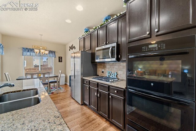 7814 Dry Willow Way, Colorado Springs, CO 80908 - kitchen with an inviting chandelier, a sink, appliances with stainless steel finishes, dark brown cabinetry, and decorative backsplash
