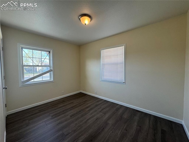 unfurnished room featuring baseboards and dark wood-style floors