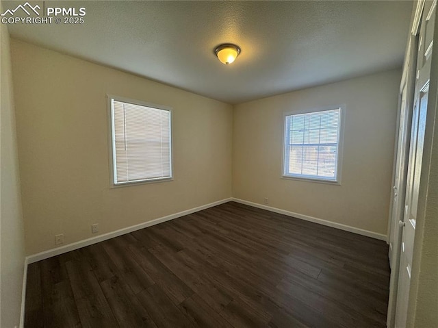 spare room featuring dark wood-style flooring and baseboards