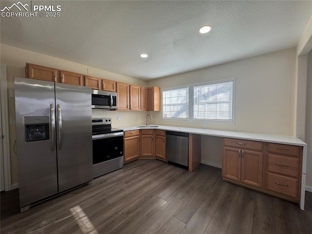 kitchen with light countertops, a textured ceiling, dark wood-type flooring, stainless steel appliances, and a sink