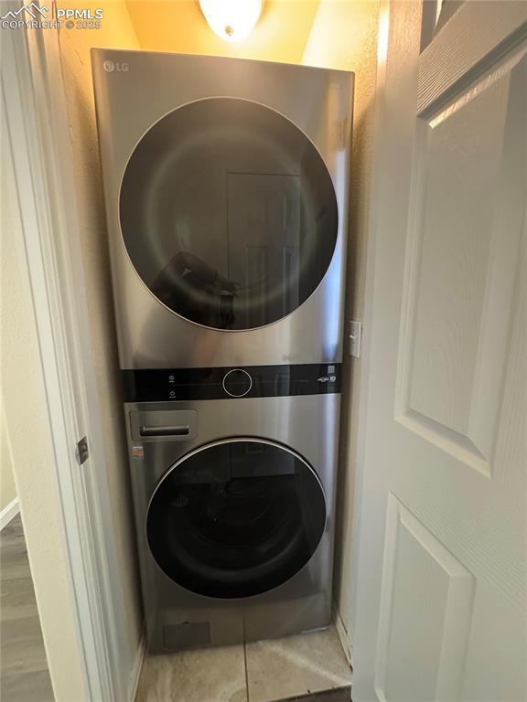 washroom with baseboards, laundry area, and stacked washer / drying machine