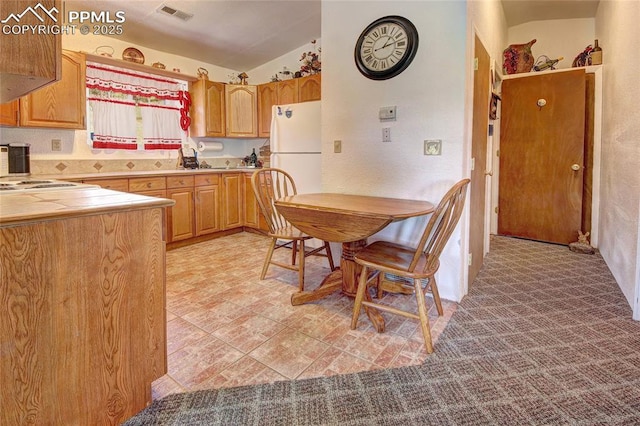 kitchen with white appliances, visible vents, lofted ceiling, and tile counters