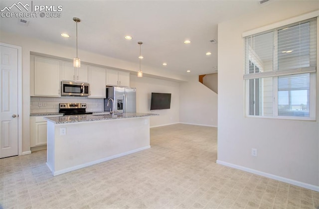 5033 Baseline Vw, Colorado Springs, CO 80920 - kitchen featuring appliances with stainless steel finishes, baseboards, white cabinets, an island with sink, and backsplash