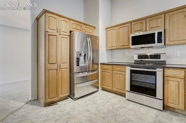 5584 Sonnet Hts, Colorado Springs, CO 80918 - kitchen featuring dark countertops, appliances with stainless steel finishes, light brown cabinetry, backsplash, and light carpet