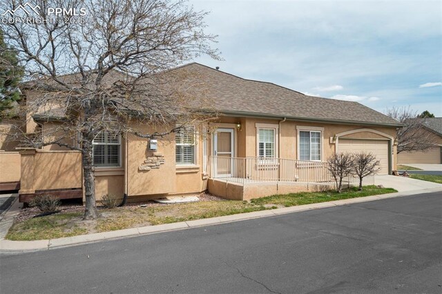 5584 Sonnet Hts, Colorado Springs, CO 80918 - view of front facade featuring a garage, stucco siding, a porch, a shingled roof, and concrete driveway