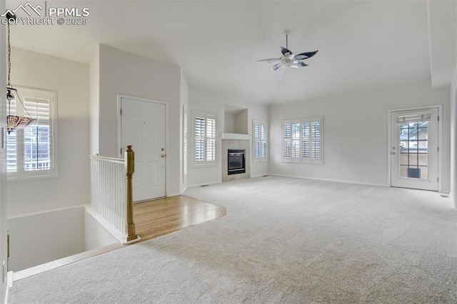 5584 Sonnet Hts, Colorado Springs, CO 80918 - unfurnished living room with baseboards, a tiled fireplace, ceiling fan, carpet floors, and vaulted ceiling