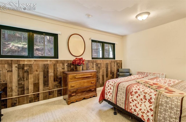 carpeted bedroom featuring wooden walls and wainscoting