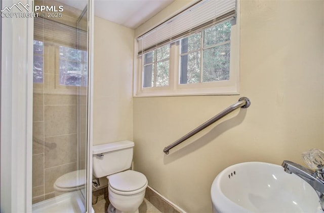 bathroom with a shower stall, toilet, baseboards, and a sink