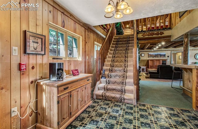 stairs with wood walls and a notable chandelier