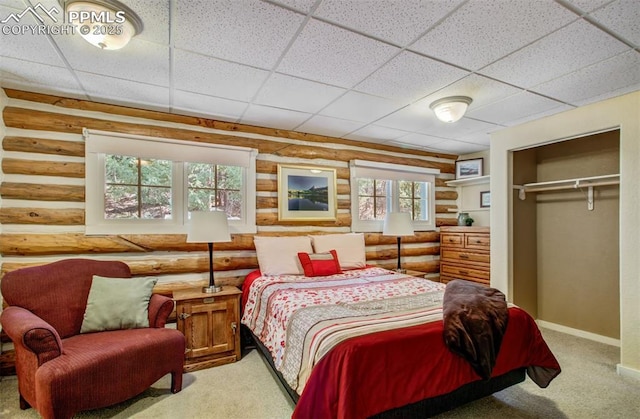 bedroom with carpet floors, log walls, a drop ceiling, and baseboards