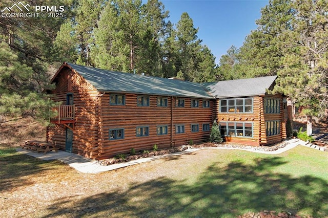 rear view of house featuring log exterior and a lawn