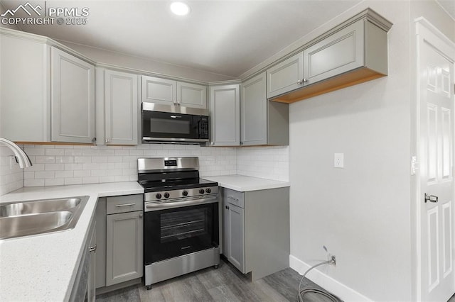 kitchen featuring gray cabinets, appliances with stainless steel finishes, wood finished floors, and a sink