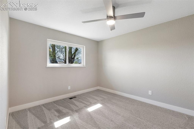 empty room with carpet, visible vents, baseboards, and ceiling fan
