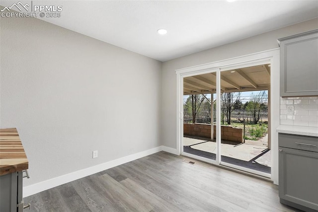 doorway featuring baseboards, wood finished floors, visible vents, and recessed lighting