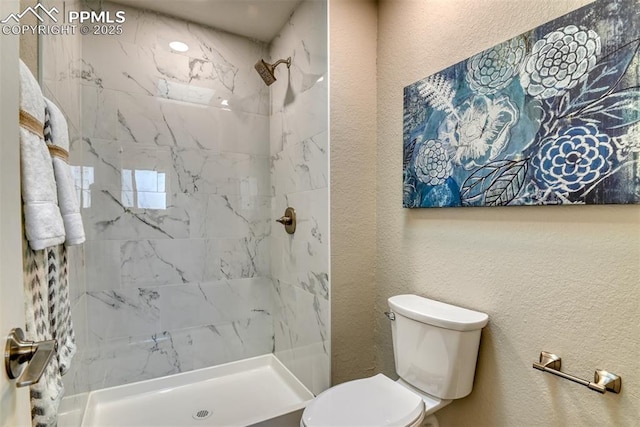 full bath featuring a shower stall, a textured wall, and toilet