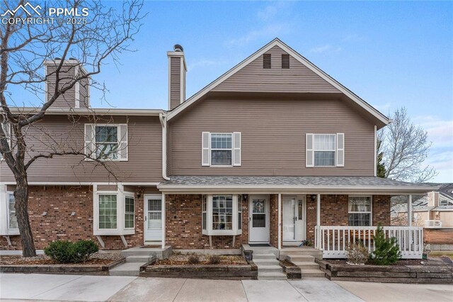 1951 Giltshire Dr, Colorado Springs, CO 80905 - view of front of house with a porch, a chimney, and brick siding