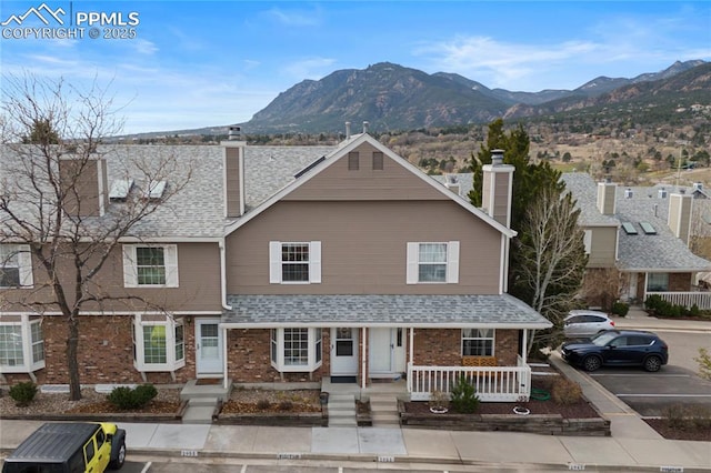 1951 Giltshire Dr, Colorado Springs, CO 80905 - view of front of property with roof with shingles, uncovered parking, a mountain view, a chimney, and brick siding