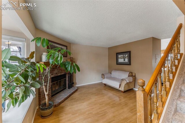 1951 Giltshire Dr, Colorado Springs, CO 80905 - sitting room featuring baseboards, a brick fireplace, wood finished floors, and a textured ceiling