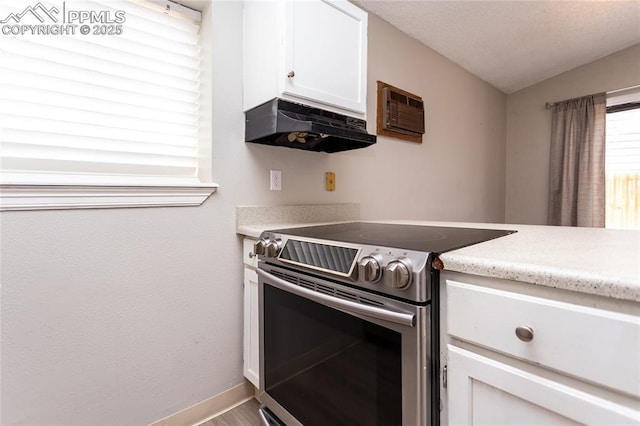 138 Hoedown Cir, Fountain, CO 80817 - kitchen with vaulted ceiling, light countertops, white cabinets, under cabinet range hood, and stainless steel range with electric cooktop